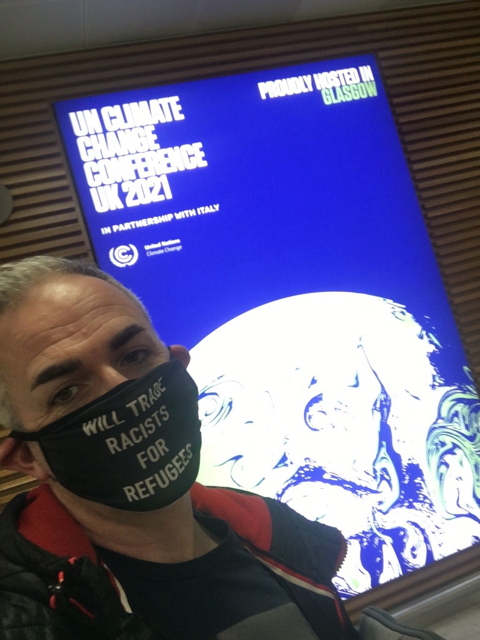 Simon by a COP26 poster in Glasgow